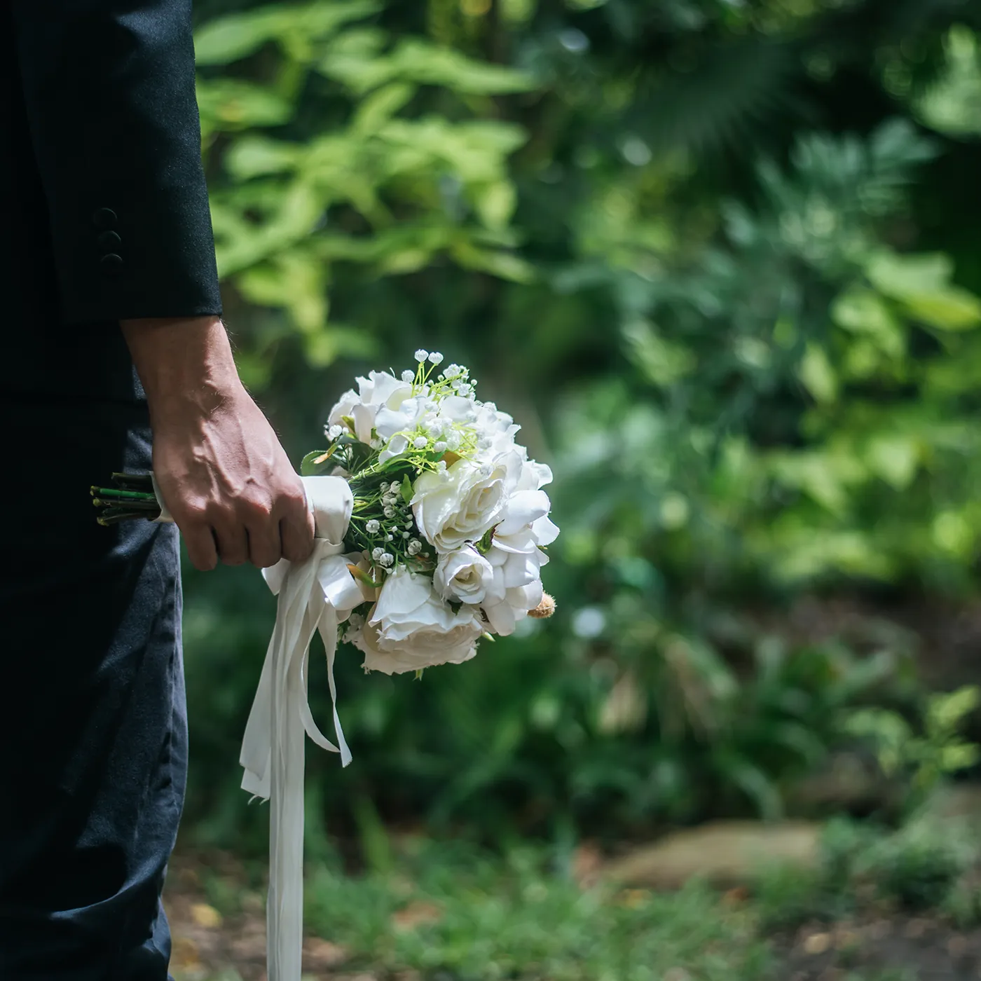 Trauernder mit weißem Blumenstrauß bei einer Erdbestattung